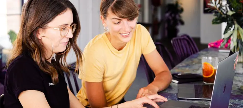 The picture shows a woman with glasses on in front of her laptop